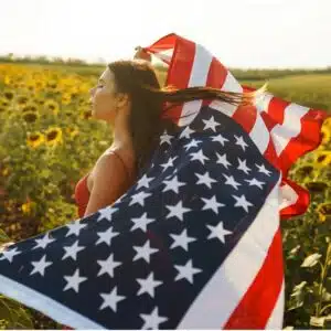Girl in flower fields with American flag blowing in the wind