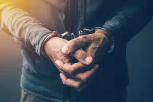 Male under arrest with hands in front of body in handcuffs, to be tried for criminal defense