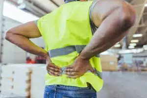 Industrial worker reaching for their back due to a lower back injury
