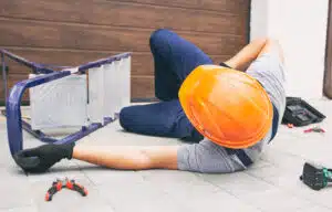 Image of an injured worker on the ground after falling from a ladder onto his back